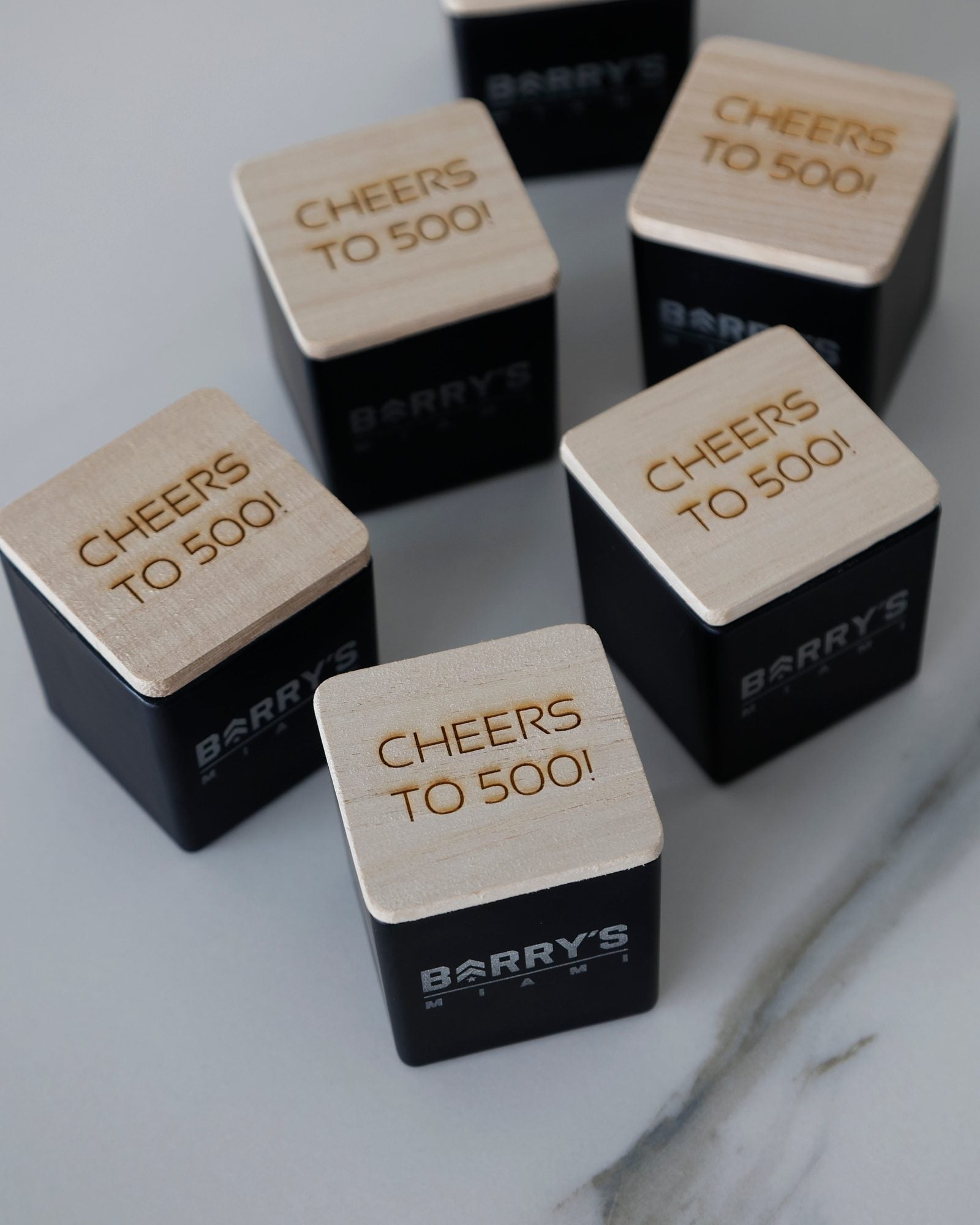 Black logo candles for Barry's Miami, the wooden lids engraved Cheers to 500!