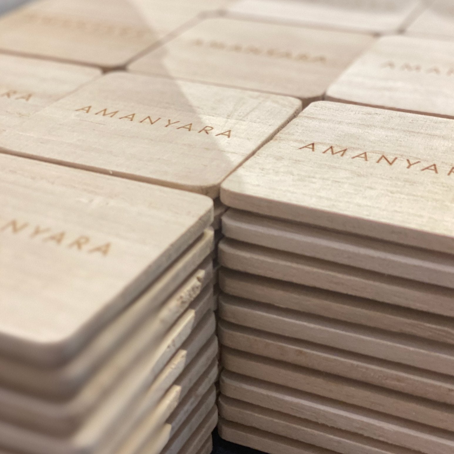 Stacks of wooden candle lids engraved with the Amanyara logo