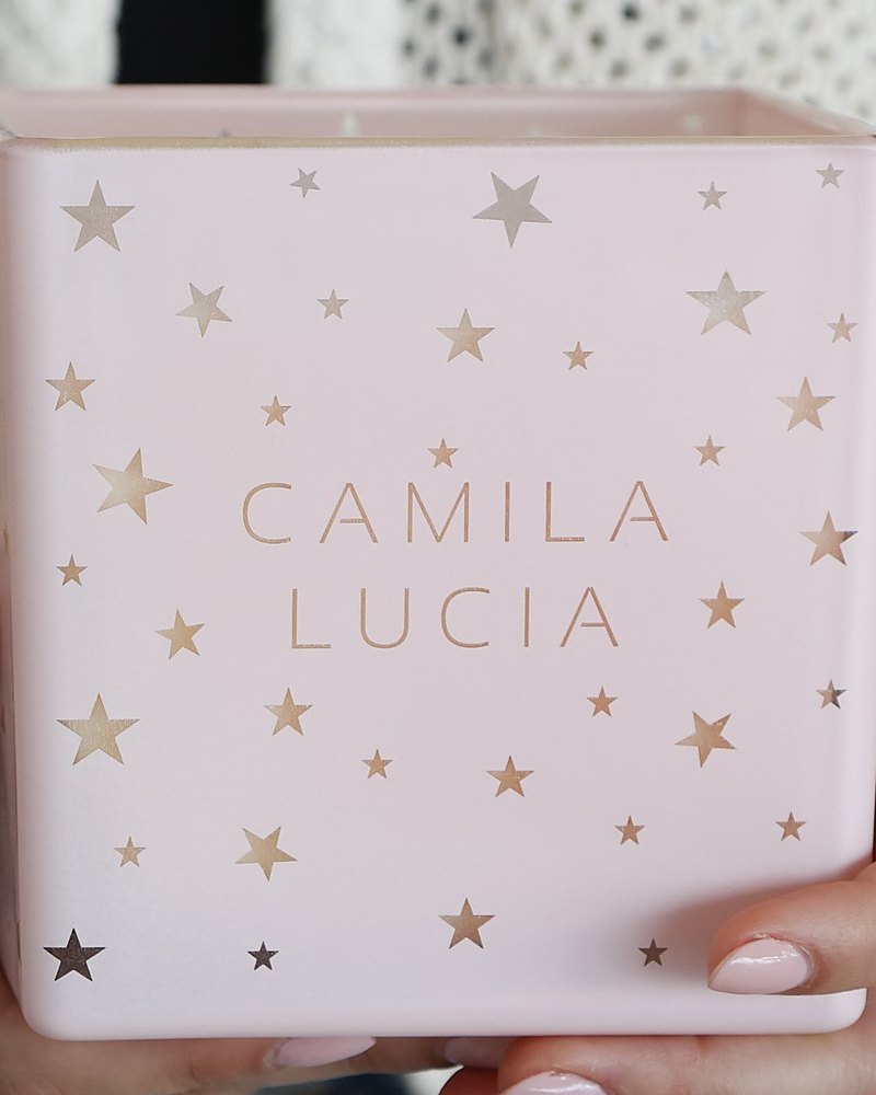 Hands holding a blush pink candle with gold stars, engraved Camila Lucia