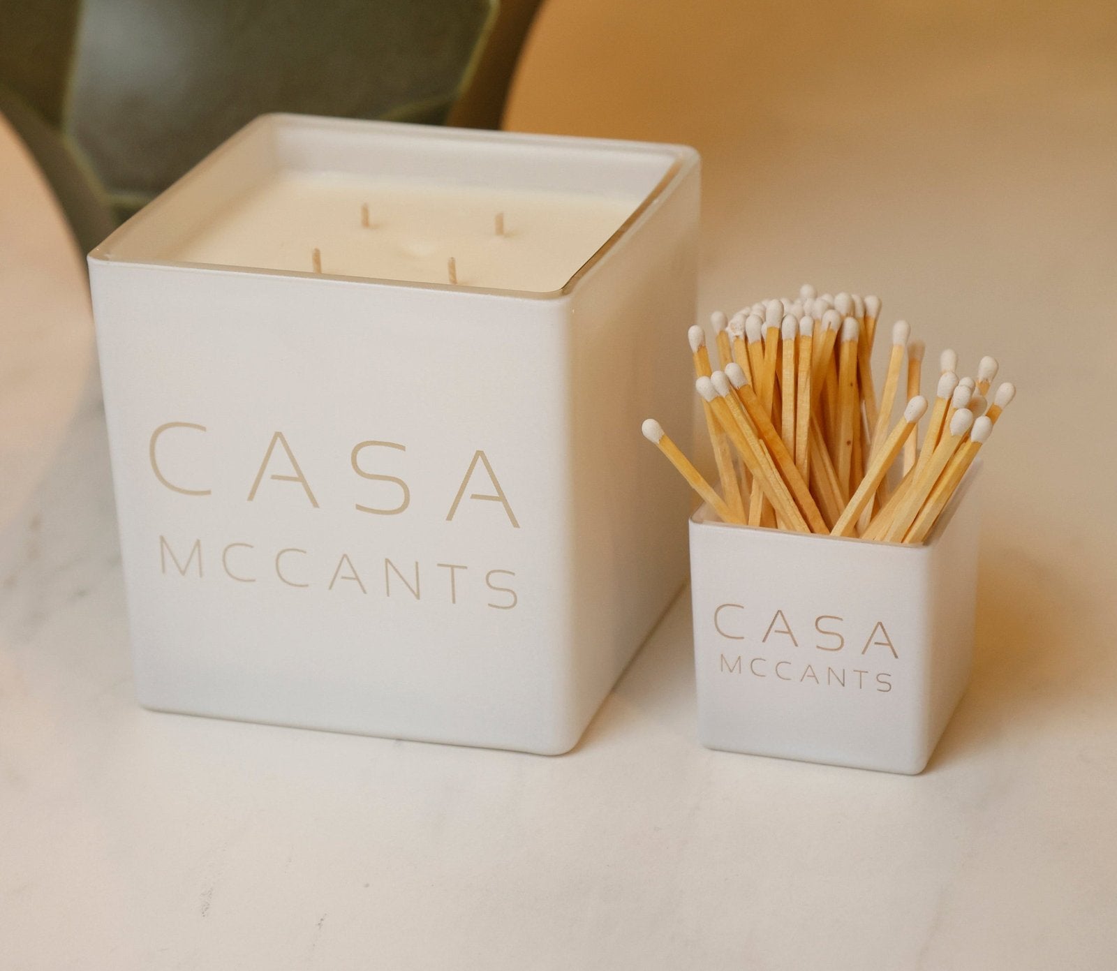 A white Casa candle and matching match holder engraved Casa McCants
