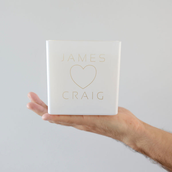 name heart name. james and craig on a white super candle, being held by a man against a white wall. perfect gift for boyfriend or girlfriend