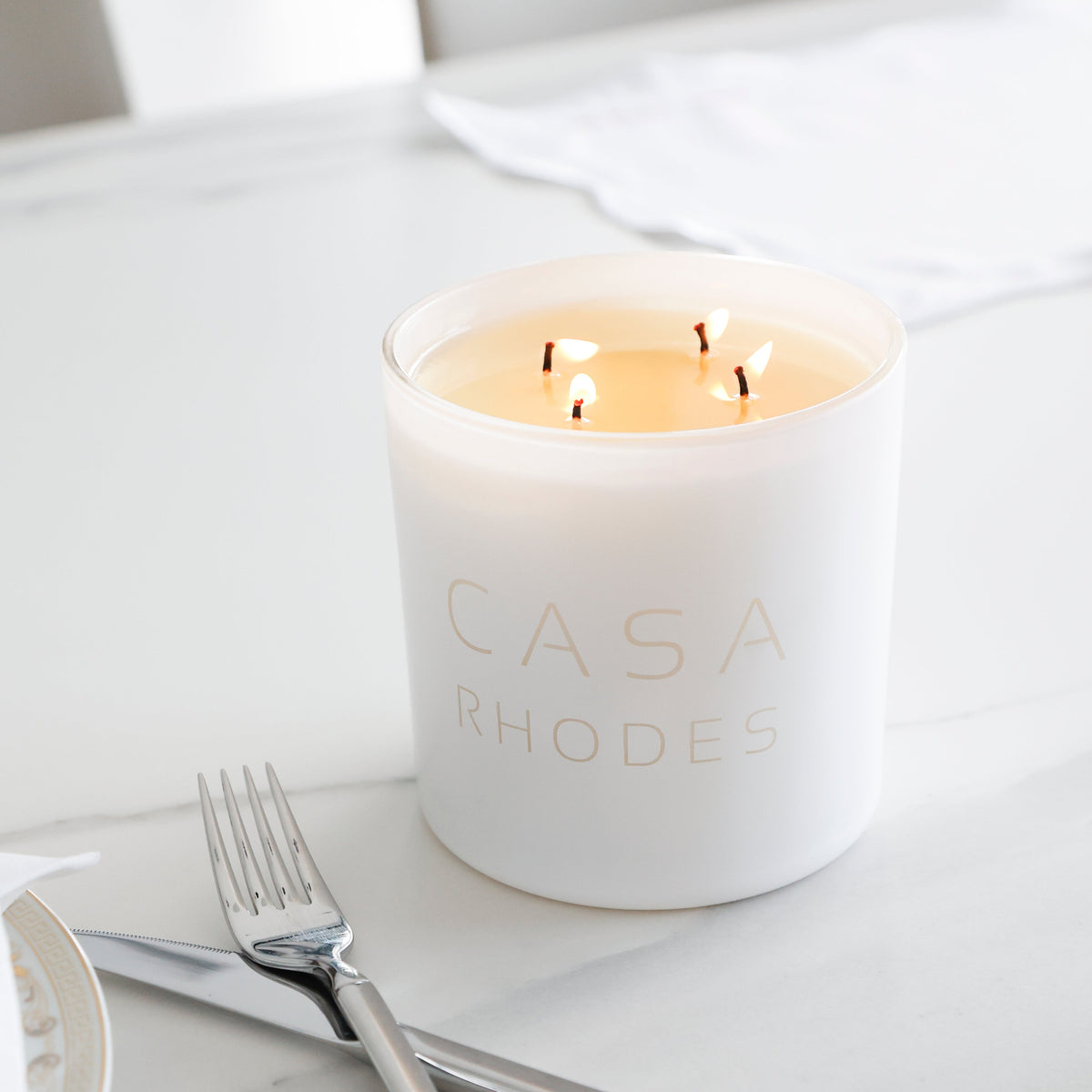 Lit white Casa cylinder candle on a dinner table