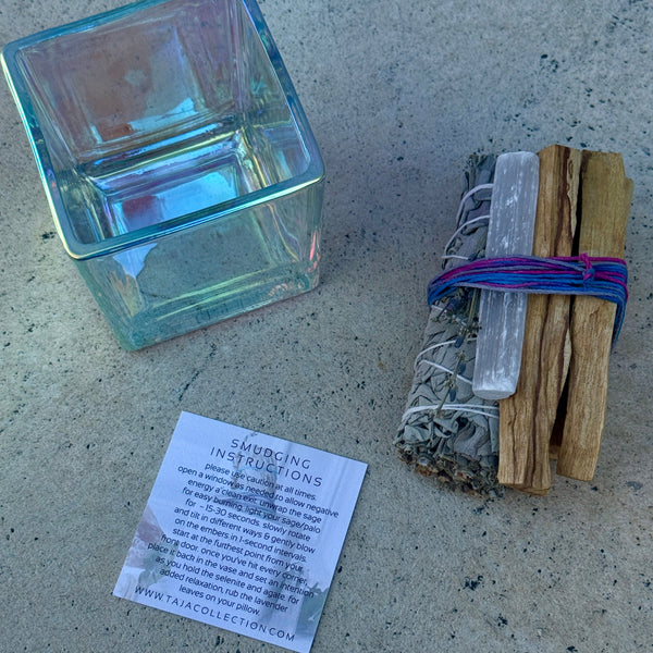 iridescent glass candle holder, smudge kit, and smudging instructions card on a concrete surface