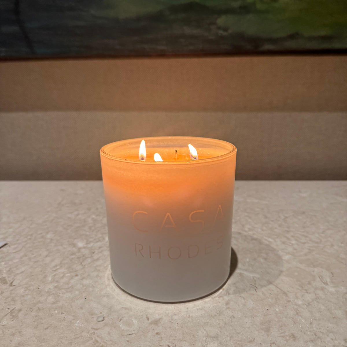 Lit white cylinder candle glowing on a stone counter