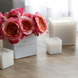 white super and cutie size I'm a cool mom candles. one super vase has been recycled as a flower holder with beautiful bright pink flowers.