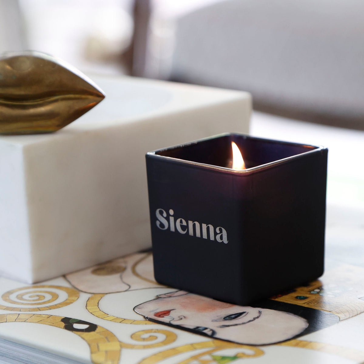 Lit black candle engraved Sienna in a bold font