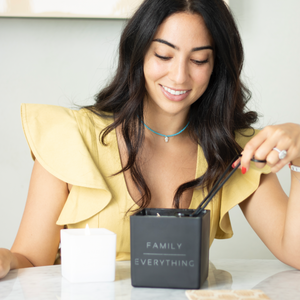 annabelle cutting the wick of a black super with family over everything on the front