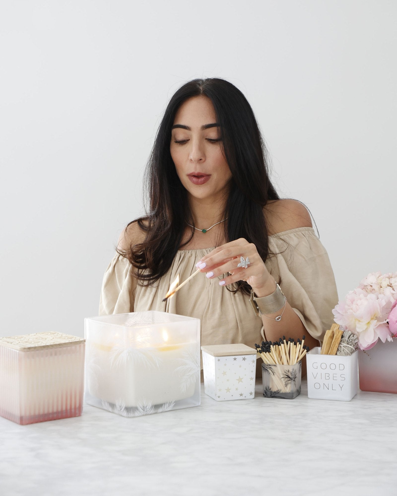 Annabelle lighting a candle at a table of TAJA candles, matches and peonies
