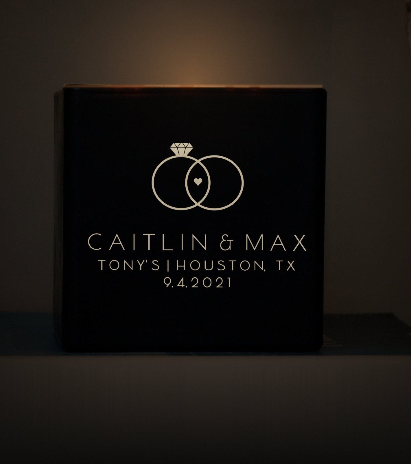 A hand lighting a black glass candle engraved for a wedding