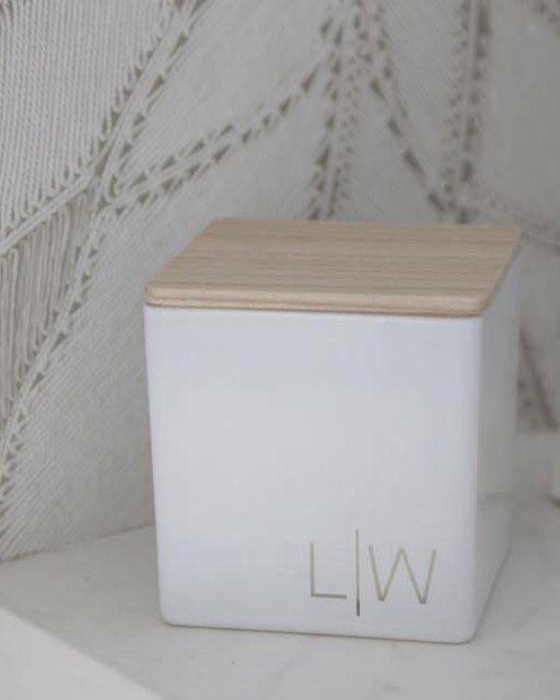 A white candle with a wooden lid engraved L | W