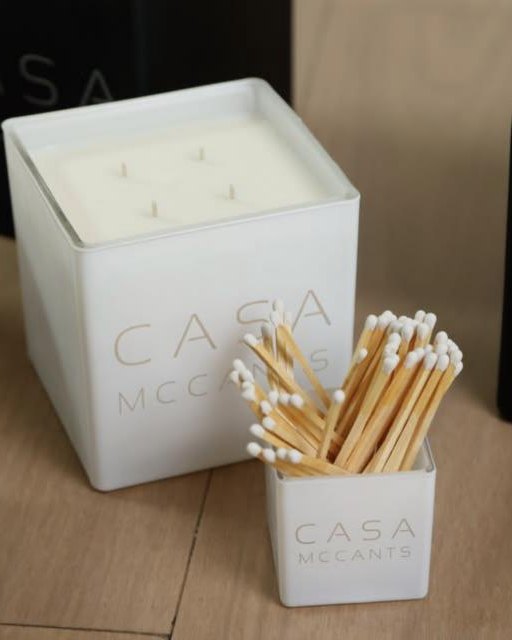 A white Casa McCants candle with a matching match holder