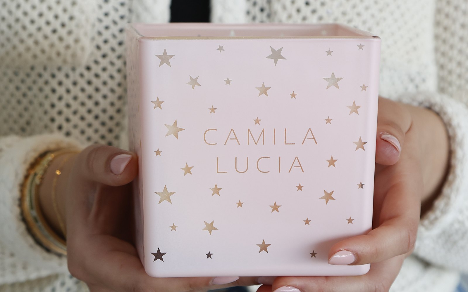 Hands holding a blush pink candle with gold stars, engraved Camila Lucia