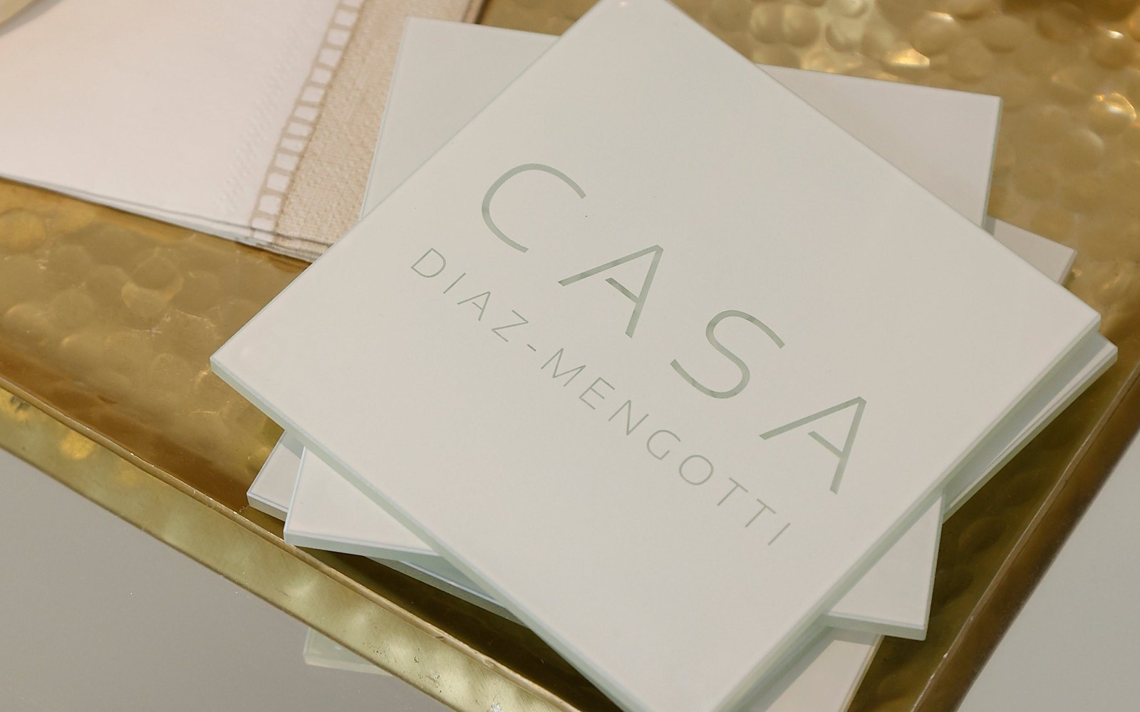 White Casa coasters engraved Casa Diaz-Mengotti on a brass tray