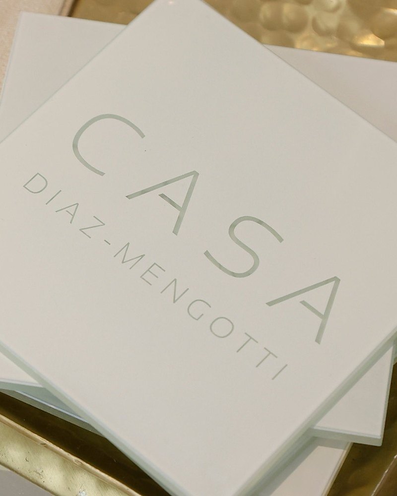 White Casa coasters engraved Casa Diaz-Mengotti on a brass tray