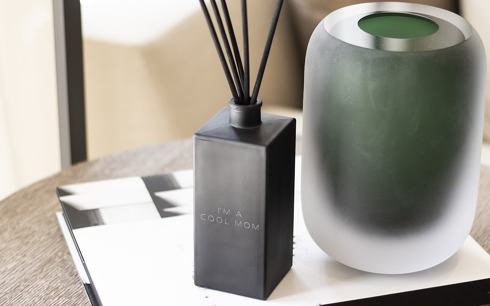 A black diffuser engraved I'm a Cool Mom beside a green glass vase