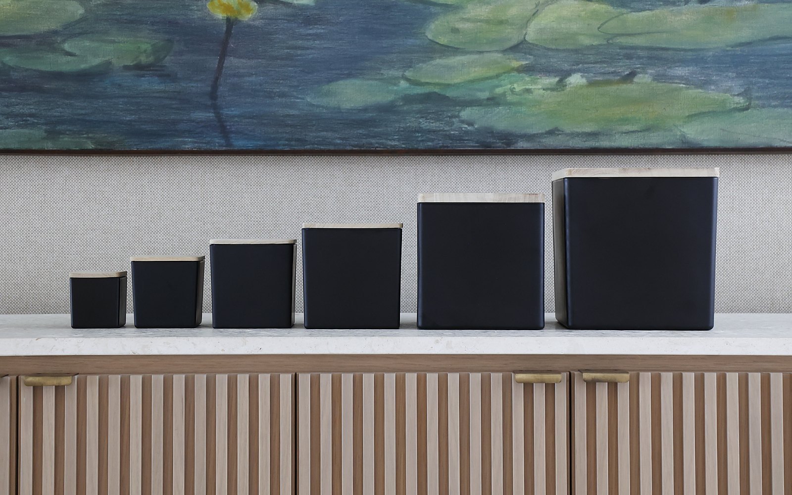 Black candles in every size, smallest to largest, on a marble counter