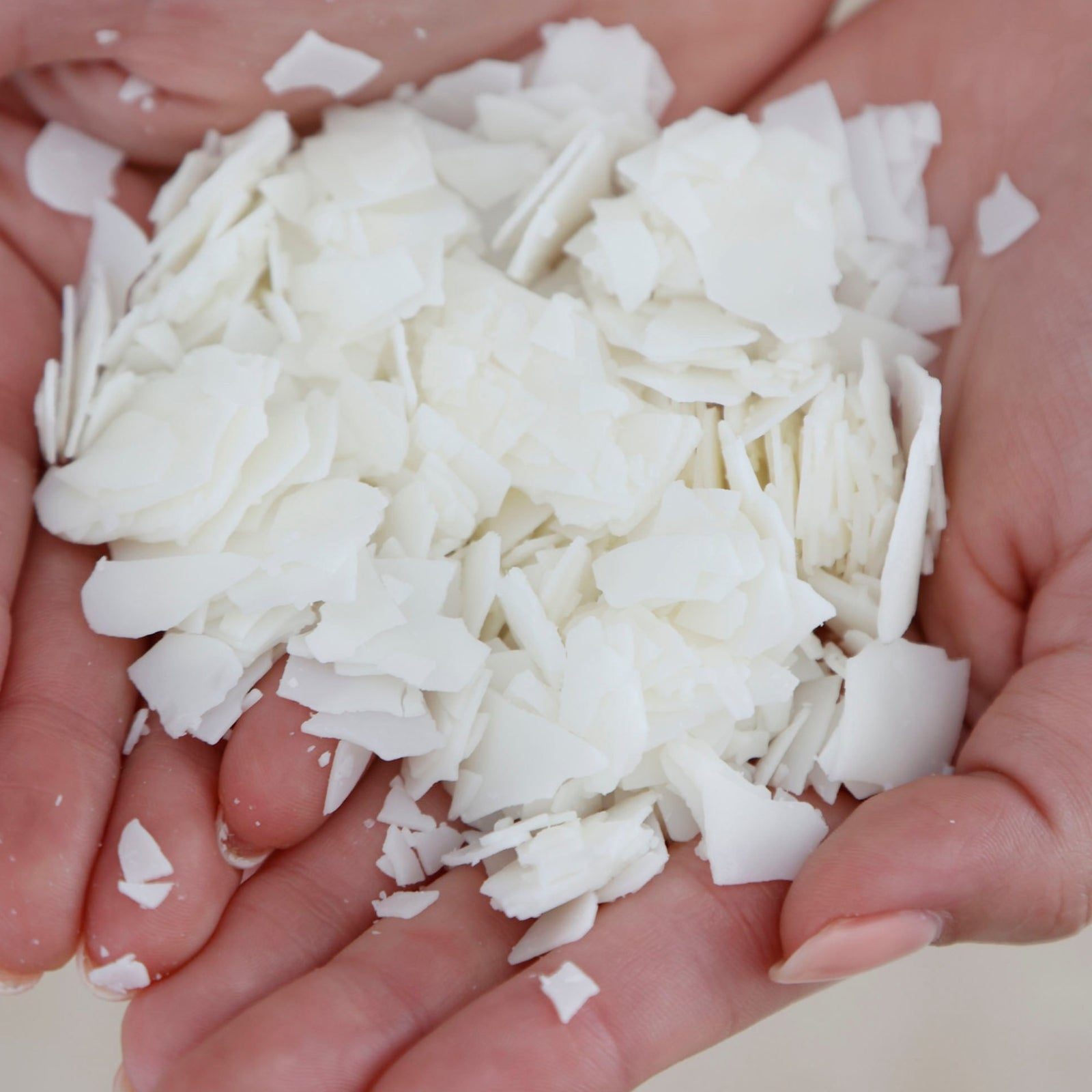 Hands holding white soy wax flakes